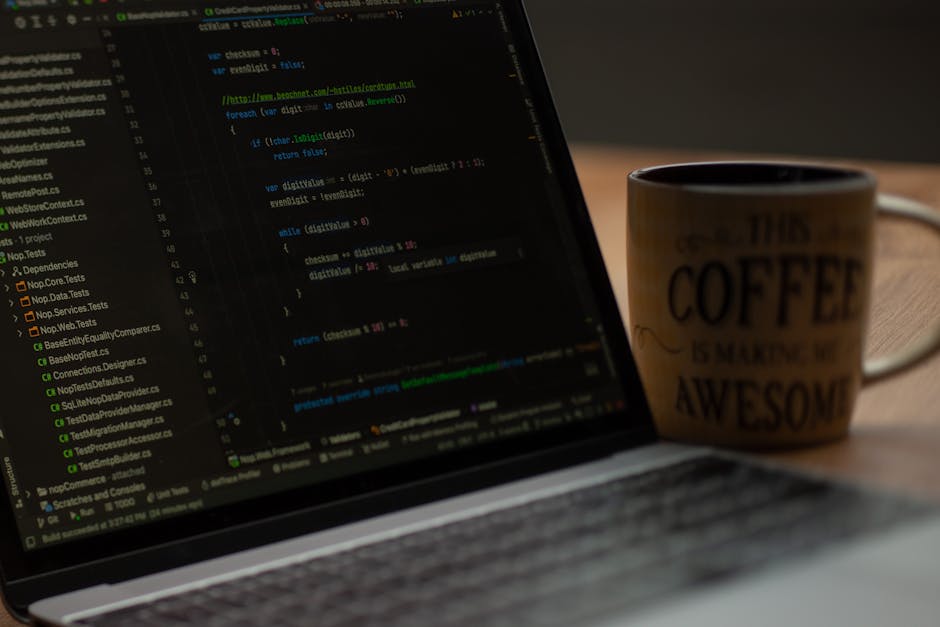 Close-up of a laptop on a wooden desk displaying lines of code on its screen, with a ceramic coffee mug to the right featuring the quote 'This coffee is making me awesome,' both illuminated by warm am